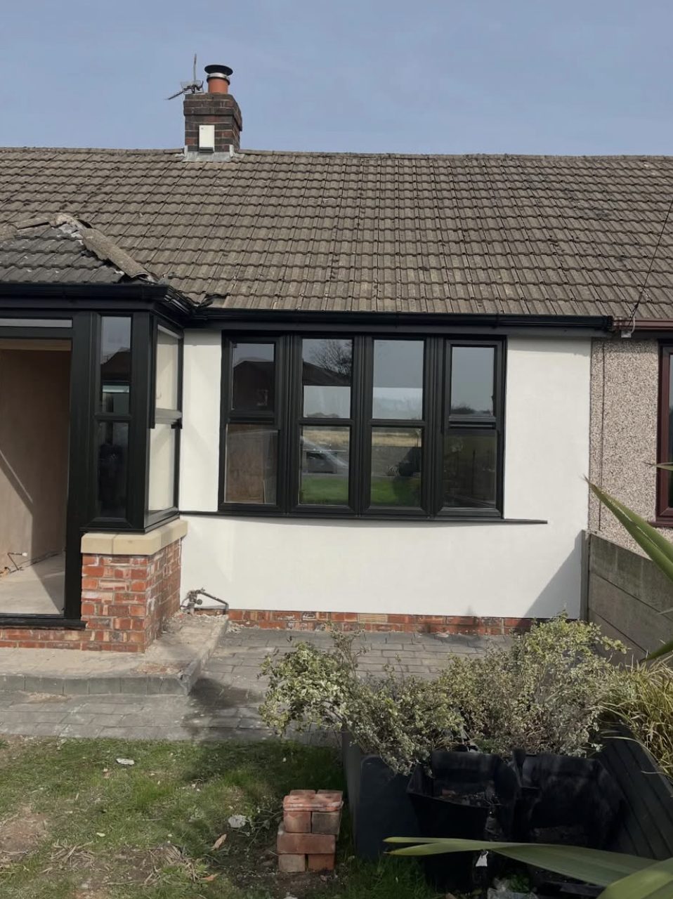 Bungalow front in smooth white render beside a neighbour's pebbledashed wall