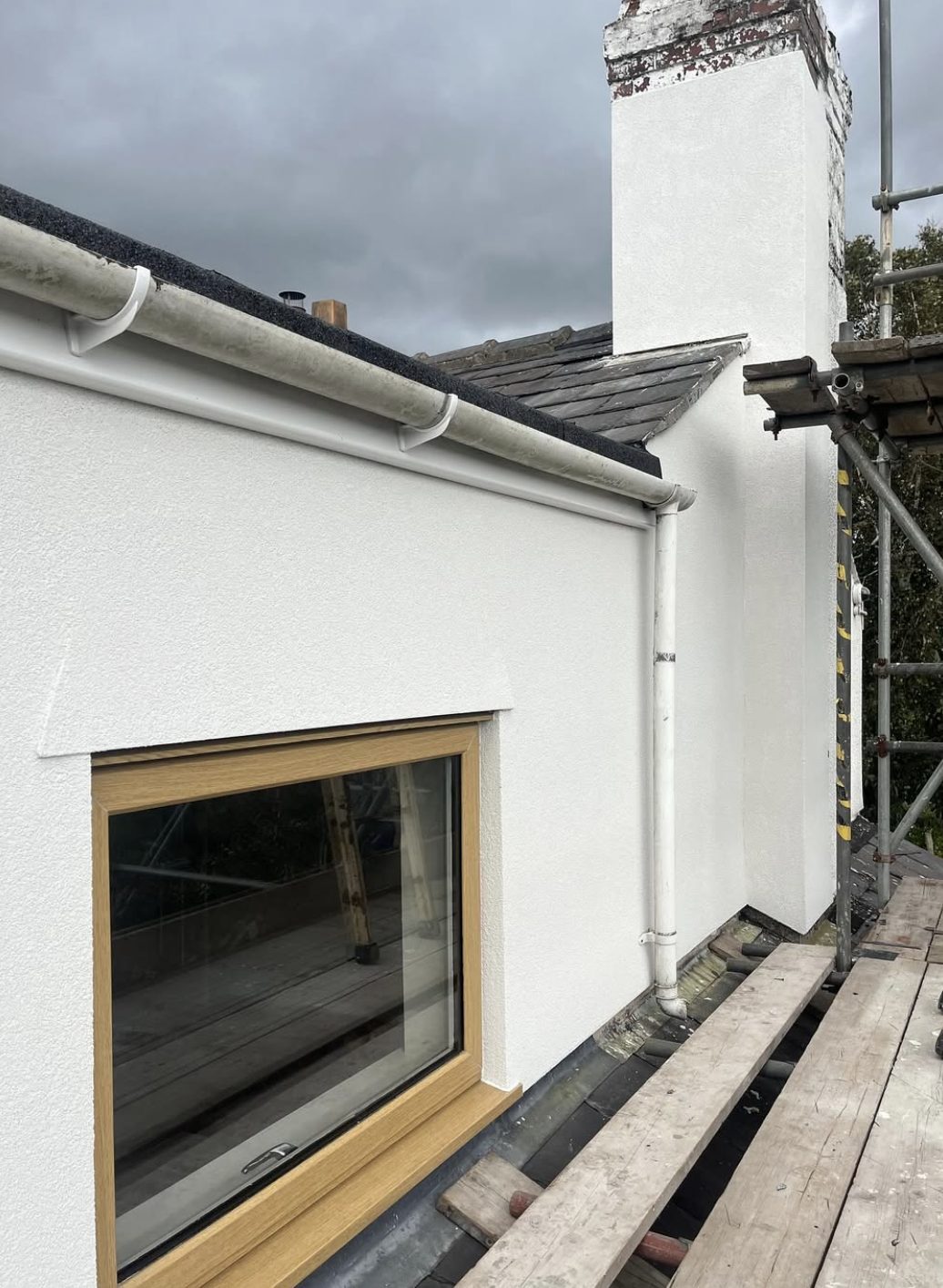 Chimney stack and dormer side freshly rendered, seen from the scaffold