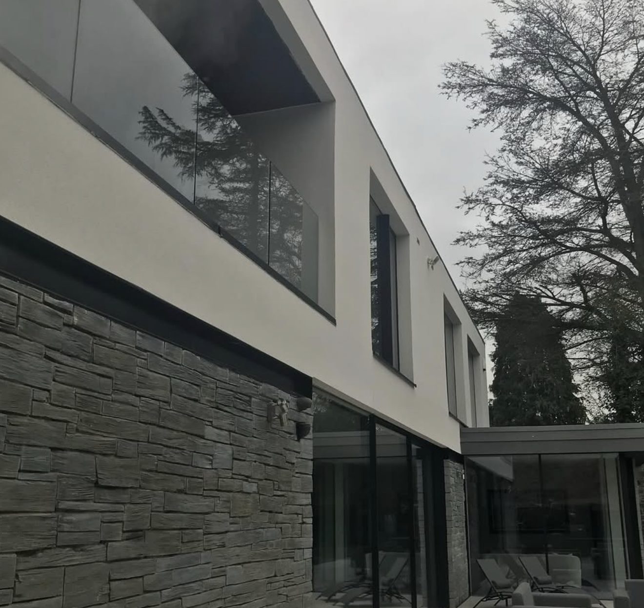 Modern house with a white rendered upper floor over dark stone cladding
