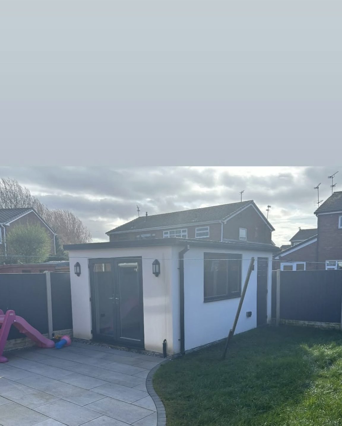 Small rendered garden room with a grey door
