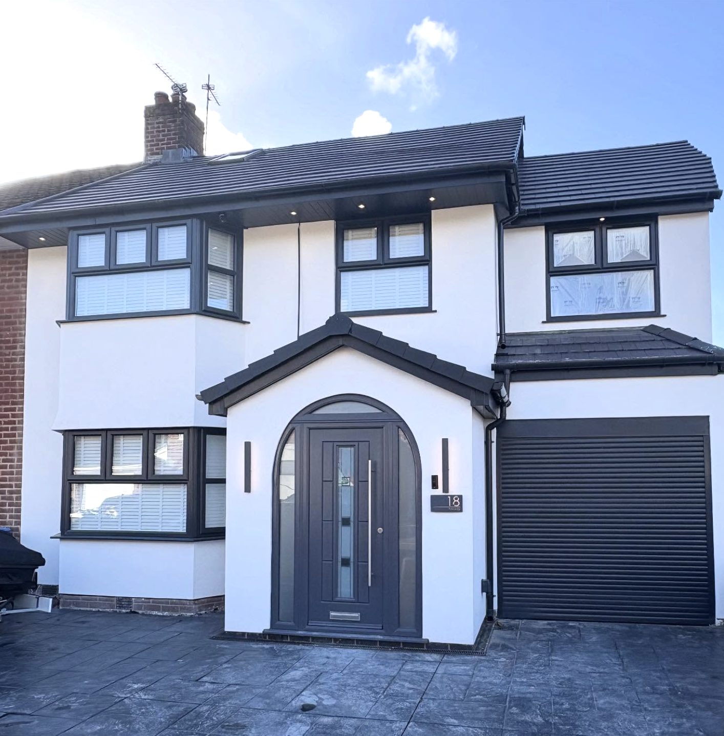 Semi-detached house in white render with an arched porch and a garage