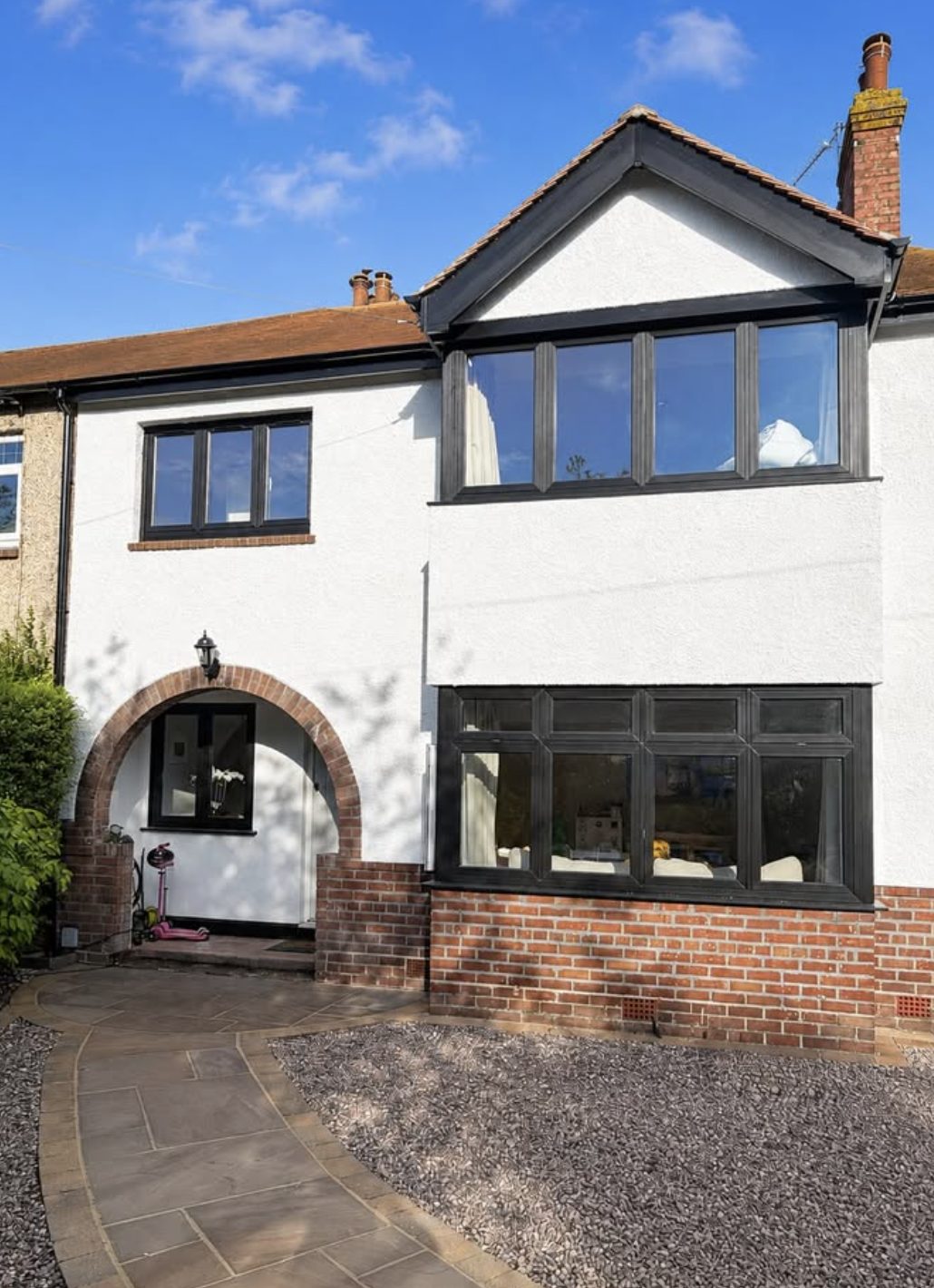 Terraced house in white render with a red brick arch over the porch